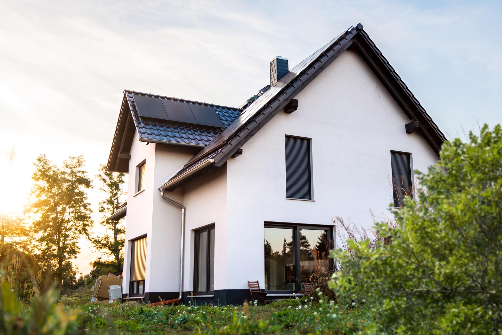 Exteriör av ett nybyggt enfamiljshus i modern skandinavisk stil med vita putsfasader och mörka fönsterramar