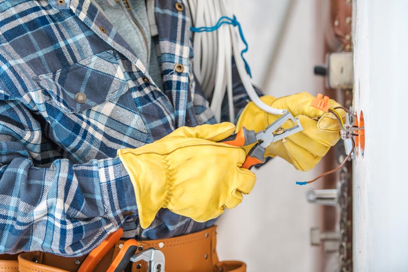 En professionell elektriker arbetar med installation av en ljuspunkt eller eluttag inuti en lägenhet