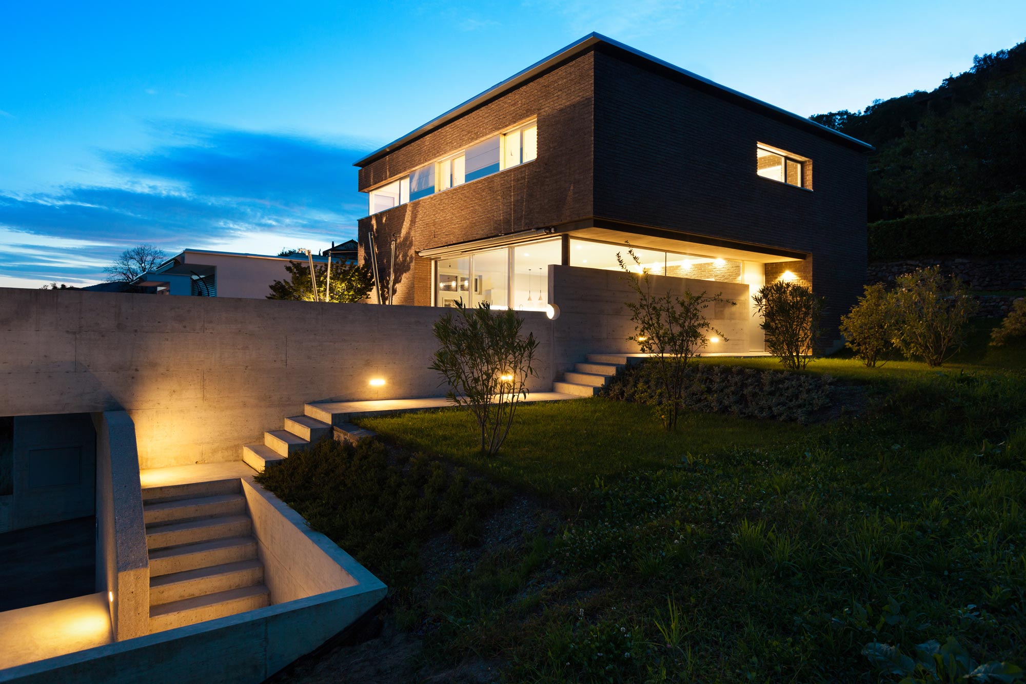 En vacker modern villa i betong och trä fotograferad vid skymning med dramatisk belysning