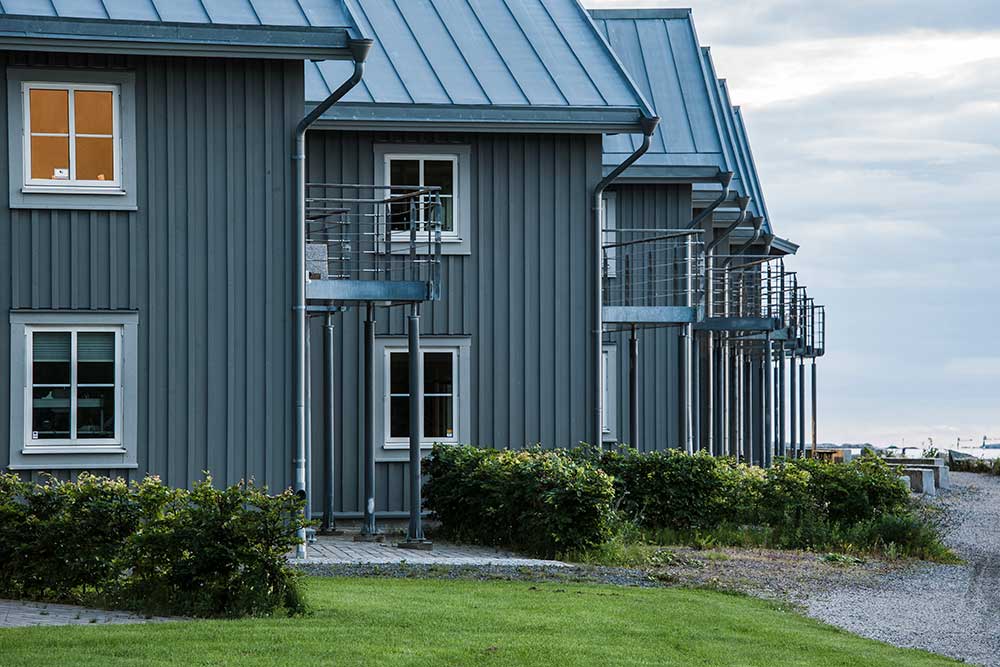 En rad moderna radhus i grått trä med vita fönster